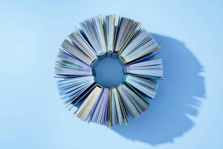 books standing on edge in circle formation on light blue background