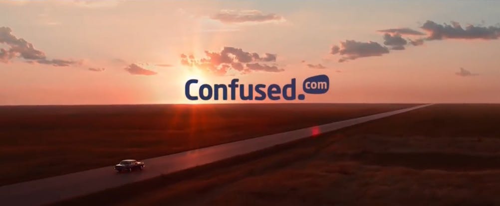 A screencap from the Confused.com 'From Confusion to Clarity' ad spot showing a car driving into the sunset with the Confused.com logo above.