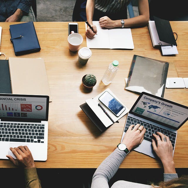 Team working across a desk with laptop computers