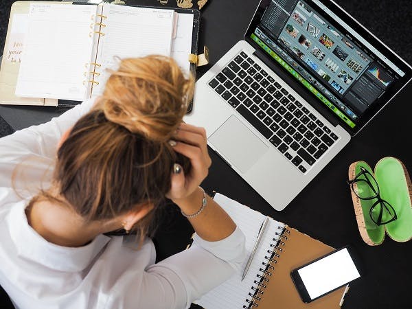 Woman sitting in front of laptop with her head in her hands