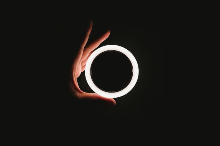 hand grasping glowing white ring on black background
