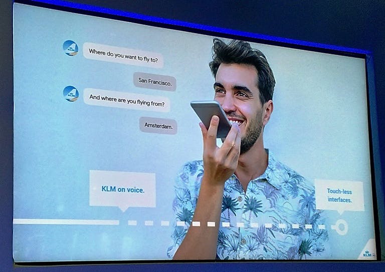 Presentation slide of a man using his mobile to converse with a KLM bot using voice.