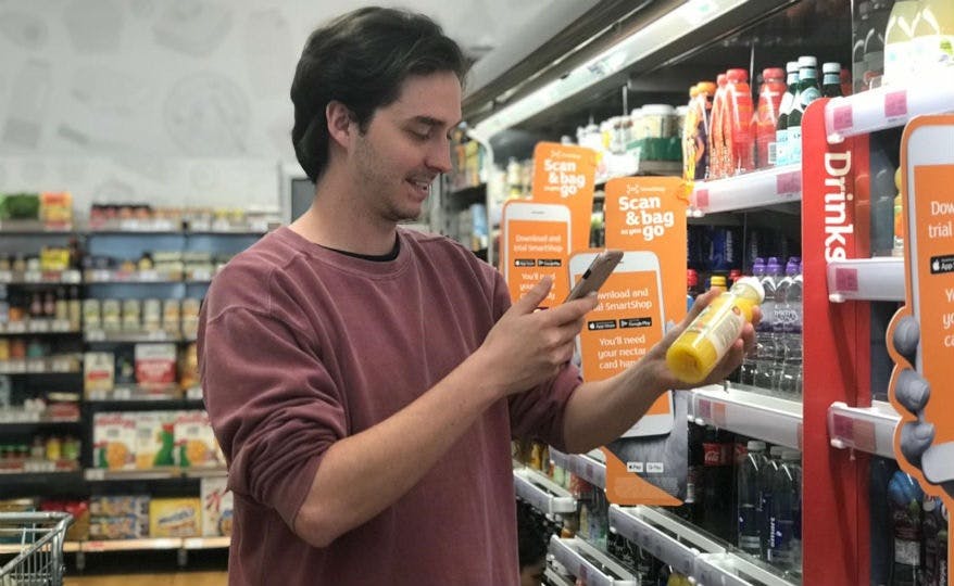 A man scans a bottle of orange juice with his smartphone in Sainsbury's Holborn Circus store.