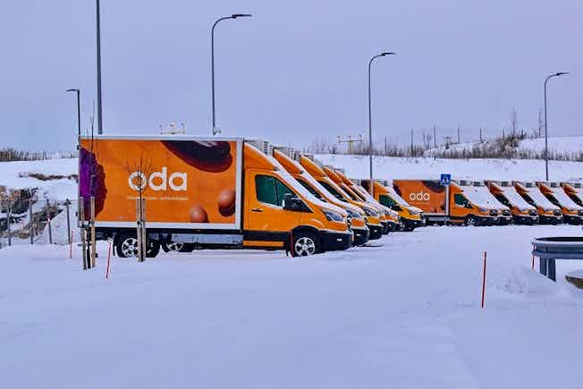 Photograph of orange Oda delivery fans lined up in the snow.