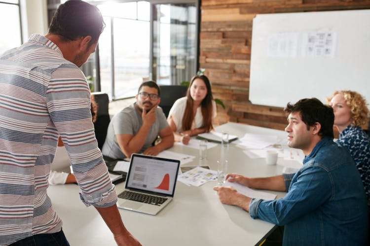 Young,Man,Giving,Business,Presentation,On,Laptop,To,Colleagues,Sitting