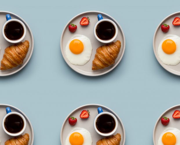 repeated plates of coffee, fried egg, strawberries and croissant in a grid pattern